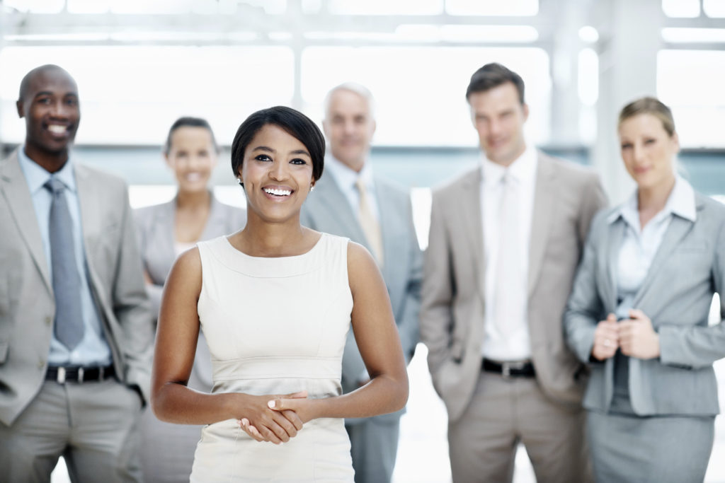 Happy ethnic businesswoman stands confidently in front of her team